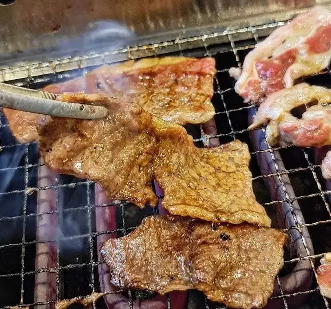 cooking meat by the grill at hey yakiniku japanese restaurant