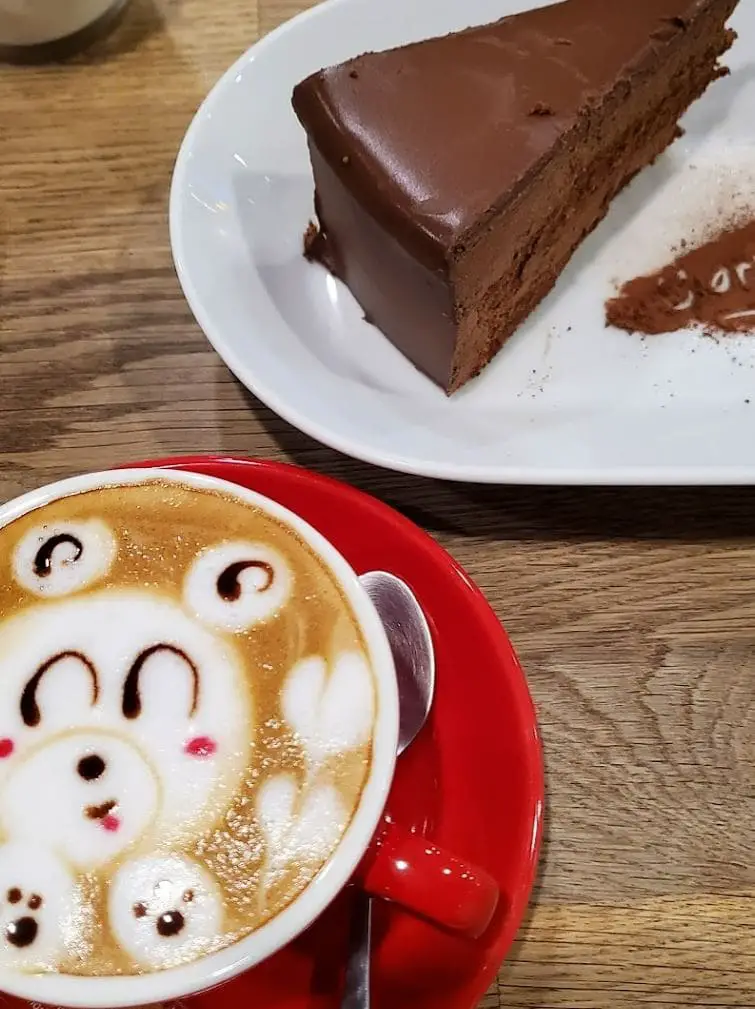 cute late art and a piece of chocolate cake on the table at chocolate origin cake shop in bugis