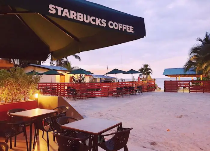 outdoor seating of starbucks with pathway to batu ferringhi beach