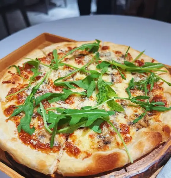 pizza with arugula on top at M'Laboori